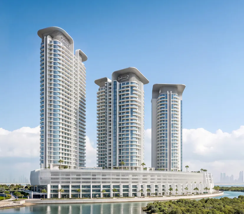 The three towers of Radisson Residences Al Reem Island on their shared waterfront podium, mangroves in the foreground and the Abu Dhabi skyline behind